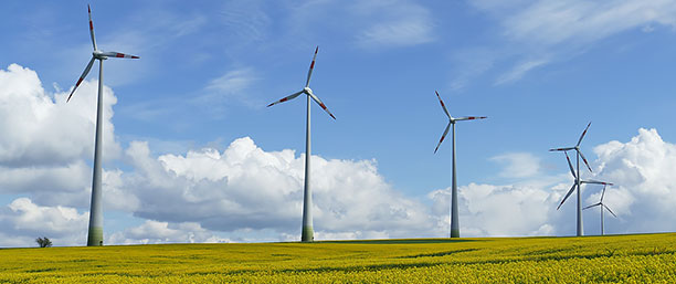 Tre vindkraftverk mot blå himmel.