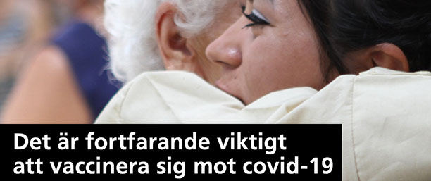 En äldre person kramar en yngre. Texten lyder: Det är fortfarande viktigt att vaccinera sig mot covid-19.