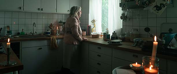En äldre dam i strömlöst kök.