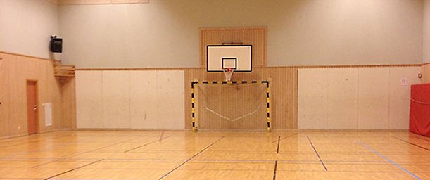 Bollebygdsskolans idrottshall. En basketkorg hänger ovanför ett svart och gult fotbollsmål.